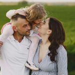 A delightful family moment captured in a lush scenic field, portraying love and happiness.
