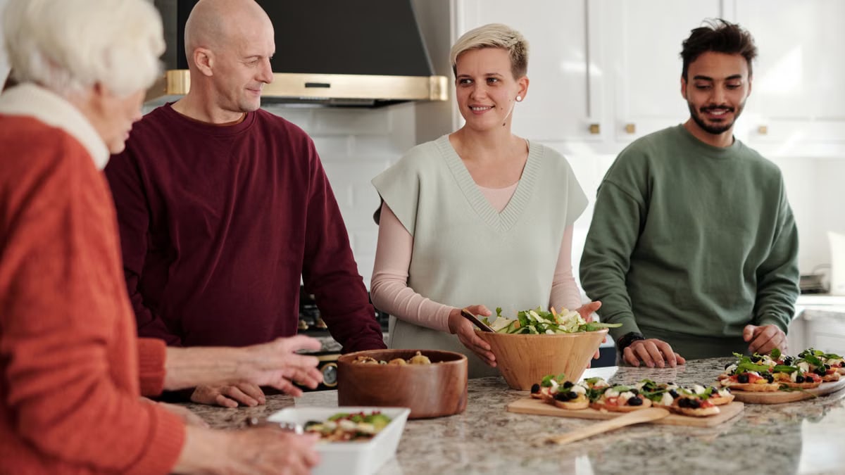 Family members preparing and enjoying a meal together in a cozy kitchen setting.